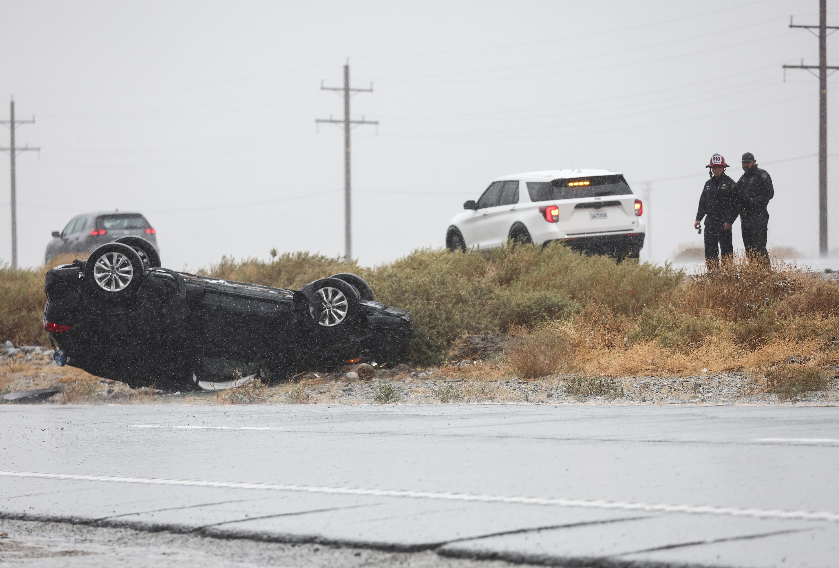 Socorristas cerca de un vehículo que volcó durante la tormenta tropical Hilary cerca de Palm Springs, California.