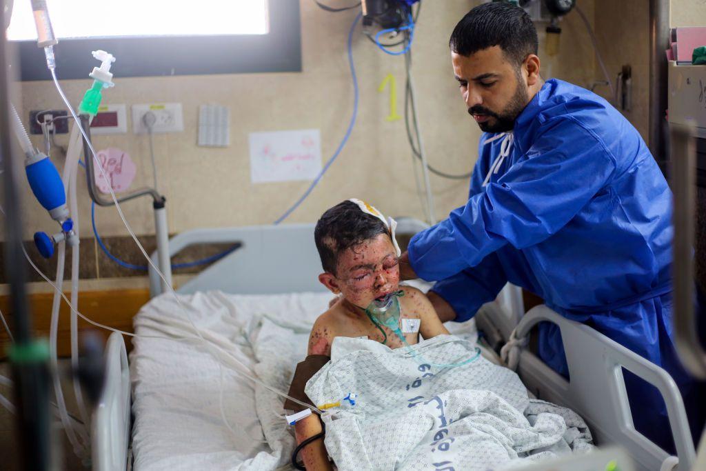 طبيب يقدم خدمات طبية لطفل مصاب في القصف