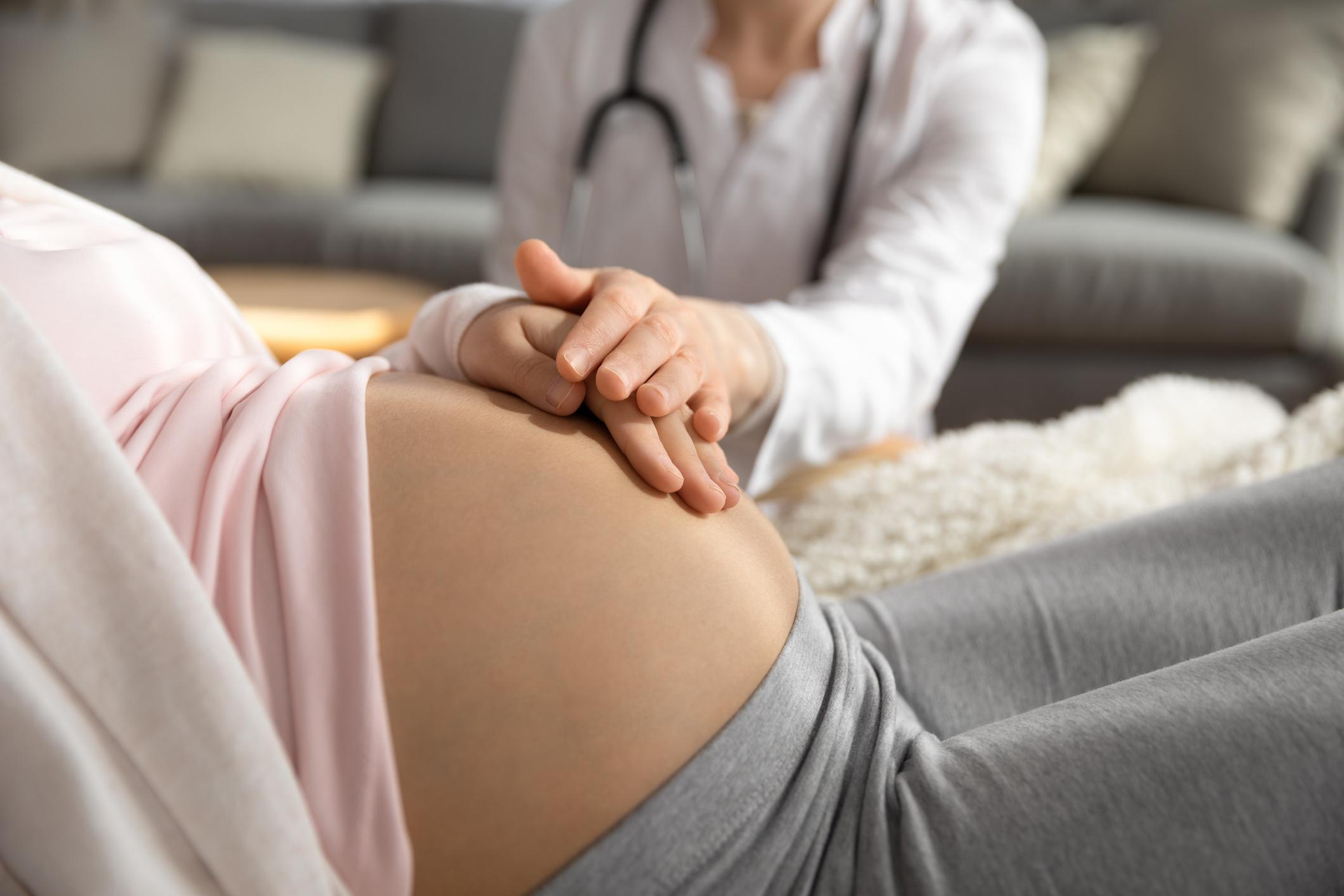 Médica examina barriga de mulher grávida