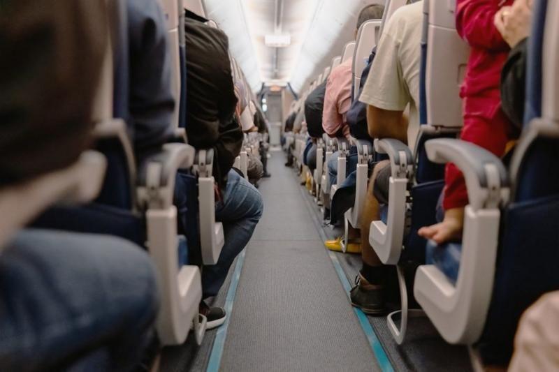 Foto de um corredor de aeronave com pessoas sentadas dentro de um avião