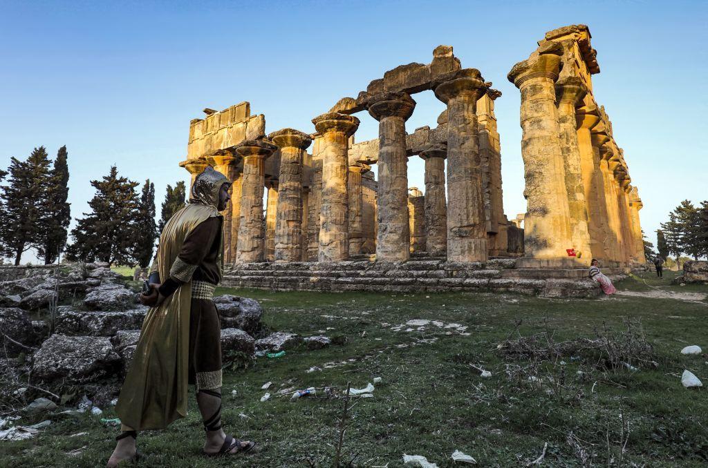 ممثل يرتدي ملابس تاريخية يمشي بالقرب من معبد زيوس في أنقاض مدينة قورينا القديمة بشرق ليبيا في 9 مارس/آذار 2021