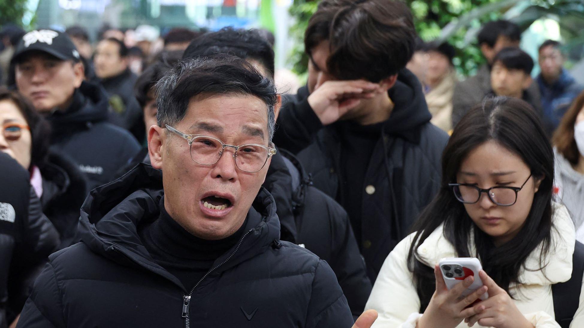 A relative of a passenger of the aircraft that crashed after it went off the runway, reacts at Muan International Airport, in Muan, South Korea, December 29, 2024.