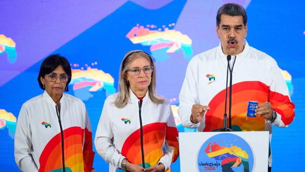 Nicolas Maduro, presidente da Venezuela, à direita, fala com membros da mídia, ao lado da primeira-dama Cilia Flores, ao centro, e Delcy Rodriguez, vice-presidente da Venezuela, à esquerda, após votar durante um referendo em Caracas, Venezuela, no domingo, 3 de dezembro de 2023. 