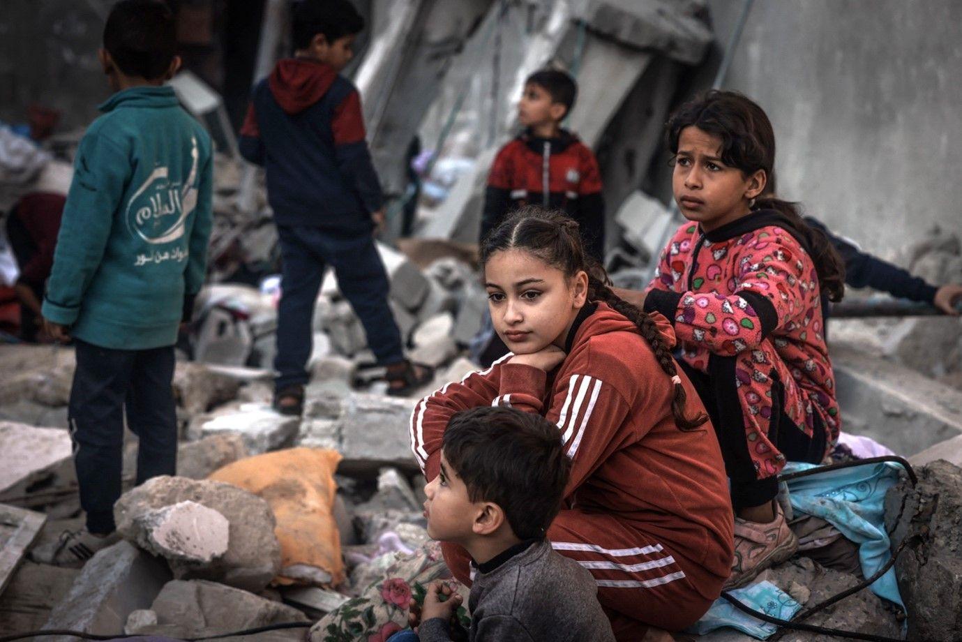 أطفال يجلسون وسط أنقاض المباني المدمرة في أعقاب القصف الإسرائيلي في رفح على جنوب قطاع غزة في 29 كانون الأول/ديسمبر 2023. 