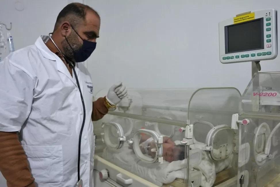 Fotografia mostra médico cuidando de bebê na encubadora