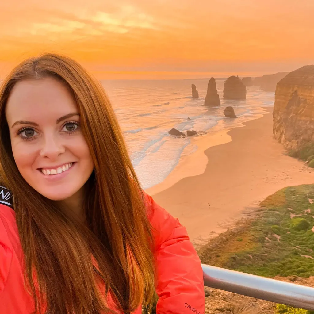 Lauren Juliff em foto em praia paradisíaca, com falésias e rochas