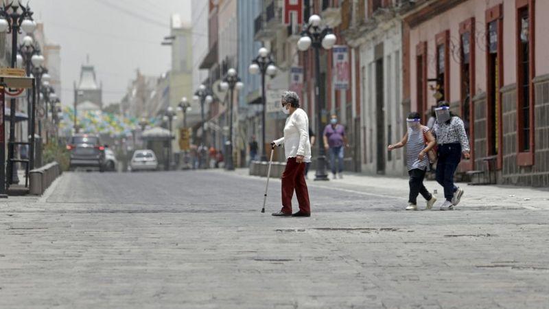 Pedestres com máscaras em uma rua de Puebla