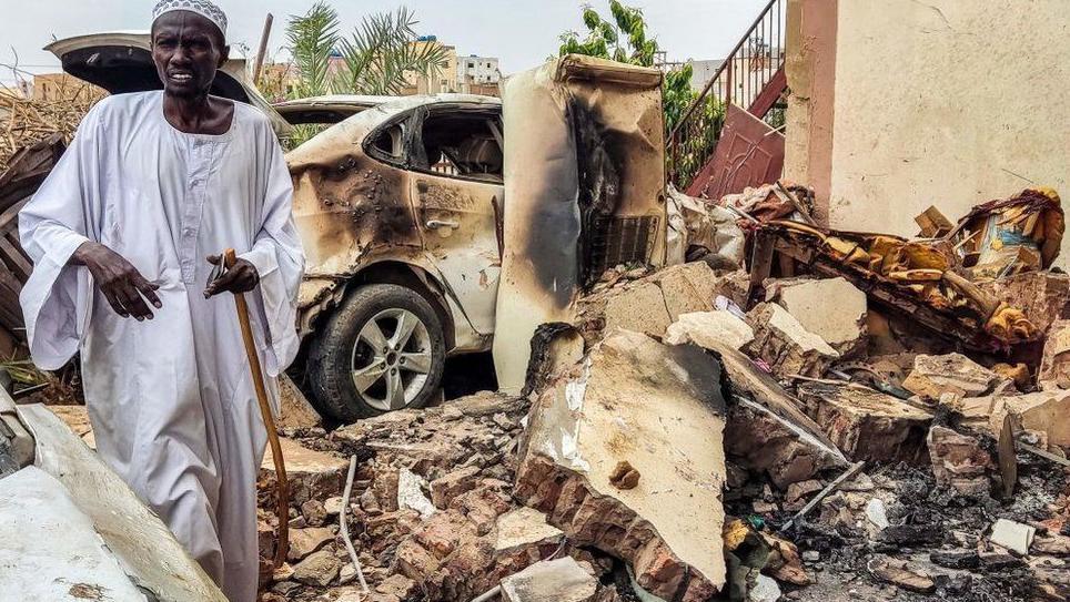 رجل يتفقد الأضرار الناجمة عن القصف خارج منزله
