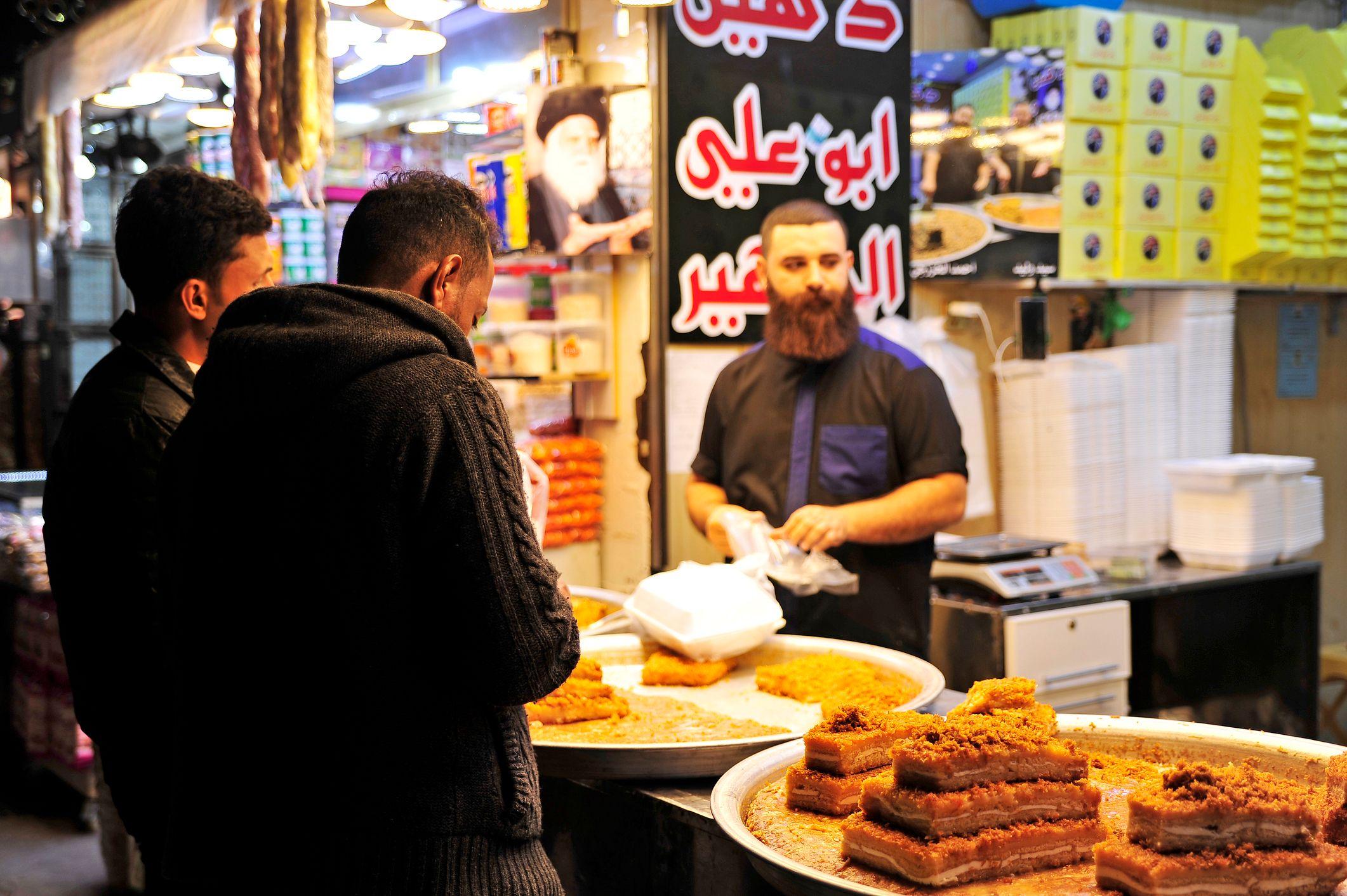 بائع حلوى يبيع حلوى موضوعة في في وعاء كبير في أحد المتاجر في ممحافظة النجف العراقية