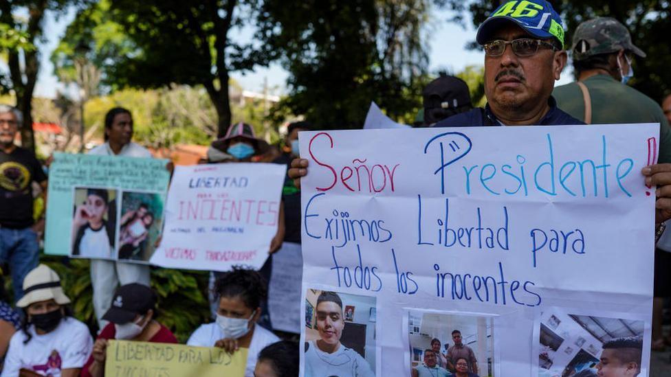 Pessoas com cartazes pedindo libertação de inocentes, incluindo fotos