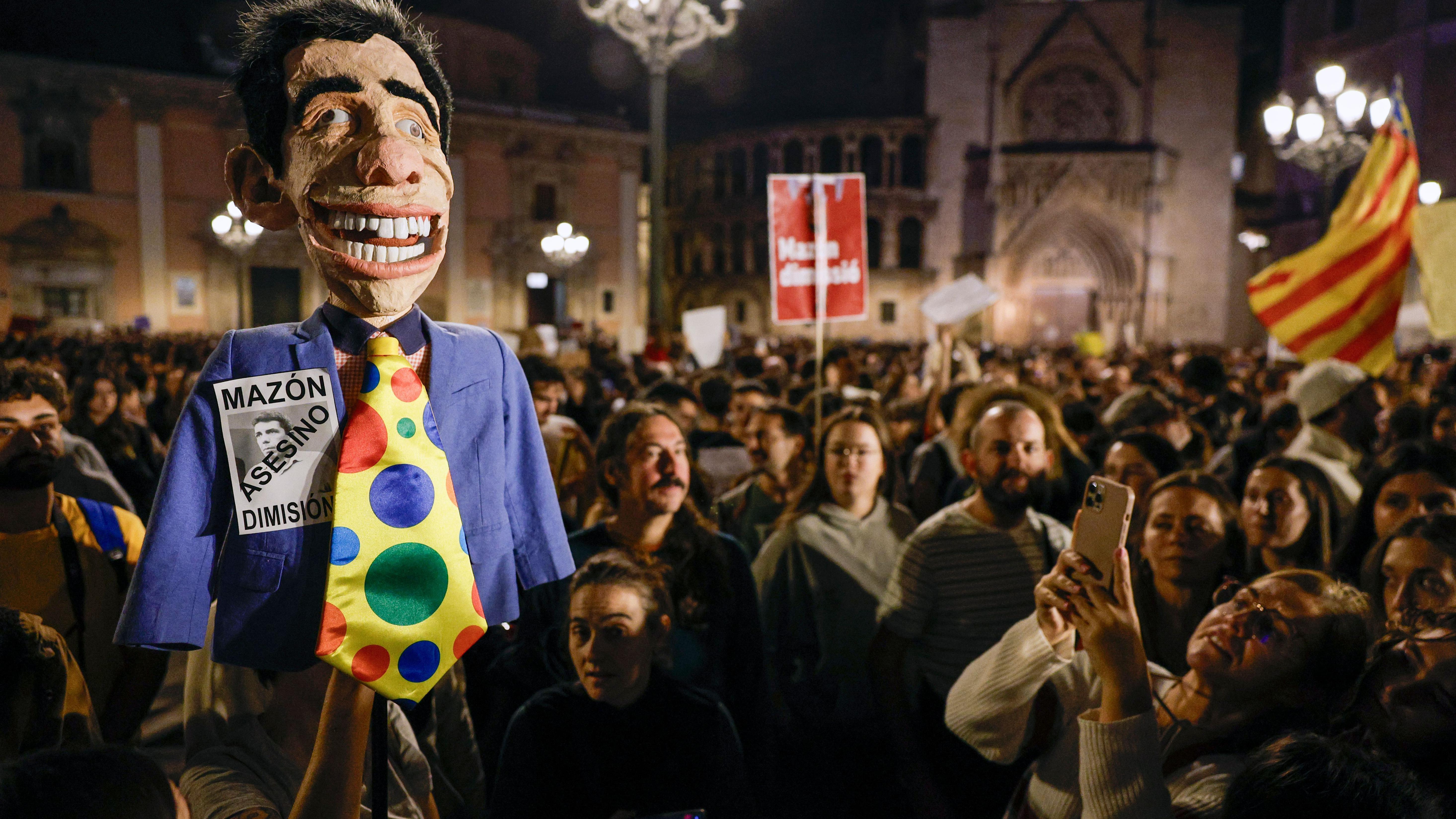 muñeco que se asemeja al rostro de carlos mazón, presidente del gobierno regional de valencia, que es cargado por un grupo de manifestantes 