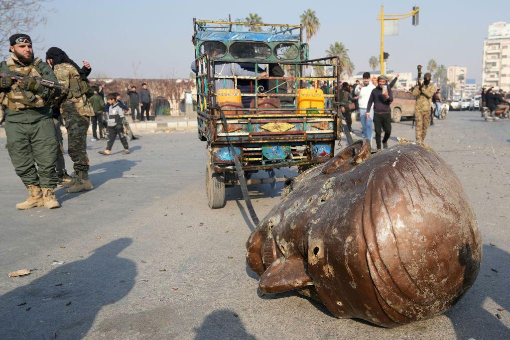 Un camión arrastra la cabeza de la estatua derribada del difunto presidente sirio Háfez al Assad por las calles de la ciudad de Hama, en el centrooeste del país, el 6 de diciembre de 2024.