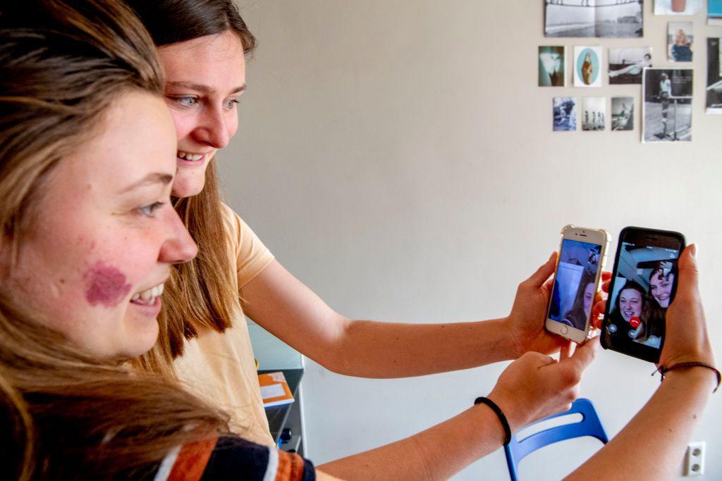 سيدتان تجريان اجتماعاً عبر مكالمة فيديو عبر هواتفهما على تطبيق مكالمات الفيديو عبر كاميرا الويب فيس تايم.