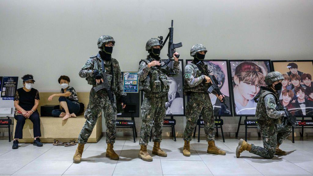 Para personel militer Korsel sedang menjalani sesi latihan di sebuah pusat perbelanjaan di Seoul, Agustus lalu. Poster para bintang K-Pop tampak di latar belakang.