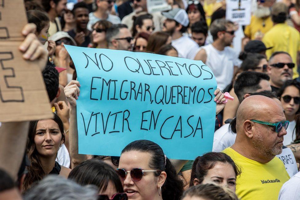 Manifestantes con una pancarta que dice: No queremos emigrar, queremos vivir en casa
