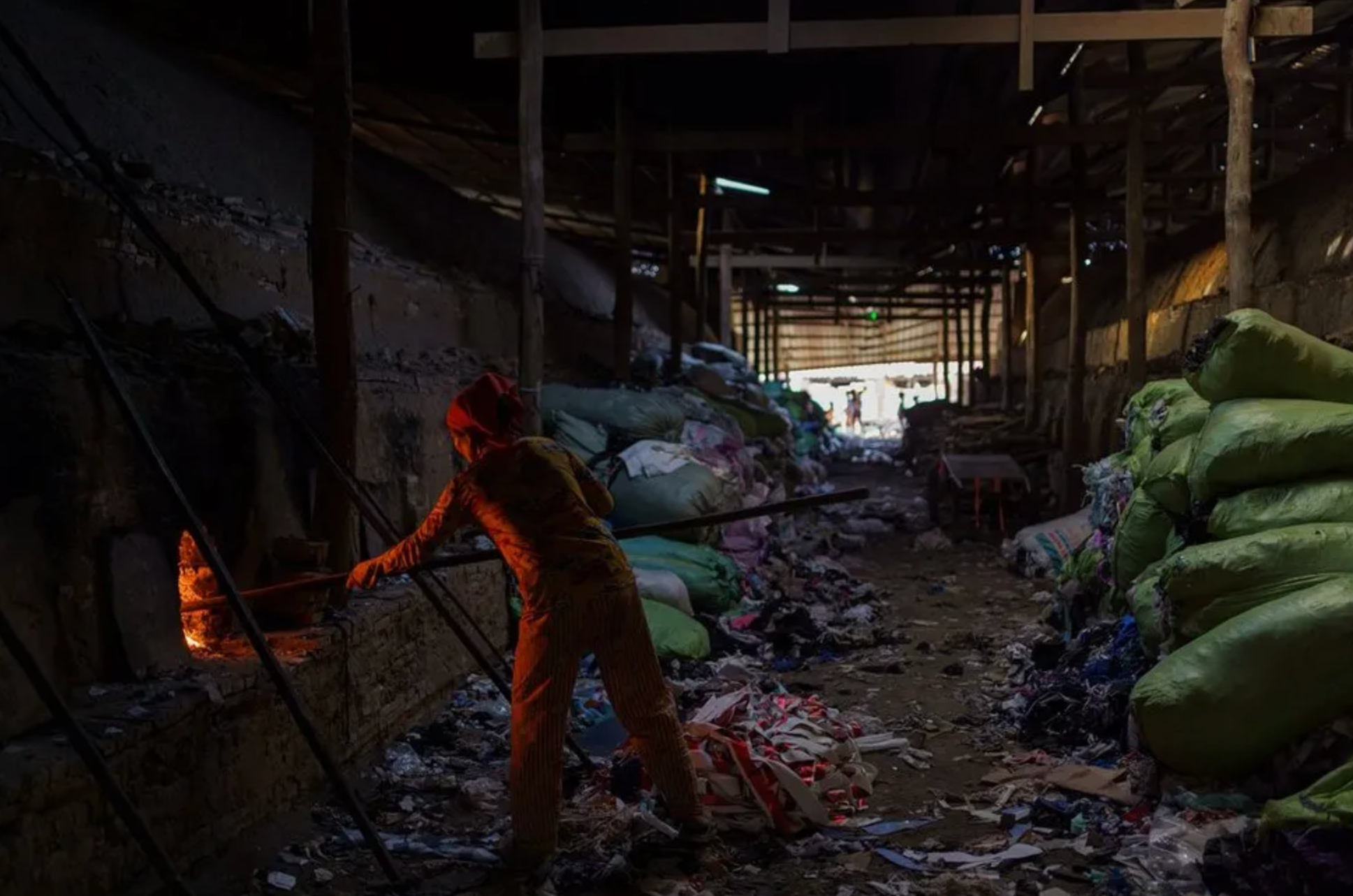 Trabalhador maneja forno com restos de roupas