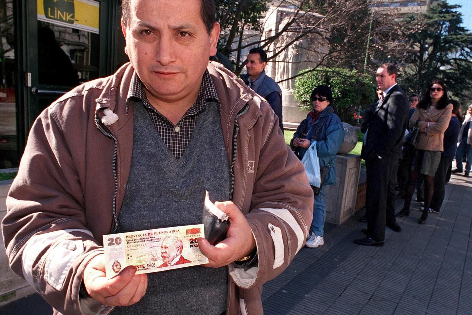 Un empleado sostiene un billete de Patacones el 21 de agosto de 2001