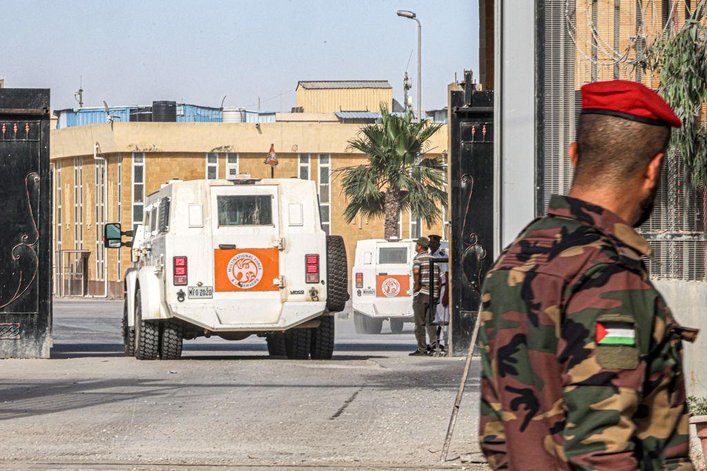 شرطي فلسطيني ينظر إلى مركبة تابعة للقوة المتعددة الجنسيات والمراقبين (MFO) تعبر باتجاه الجانب المصري من معبر رفح الحدودي في جنوب قطاع غزة في 12 يونيو 2023.