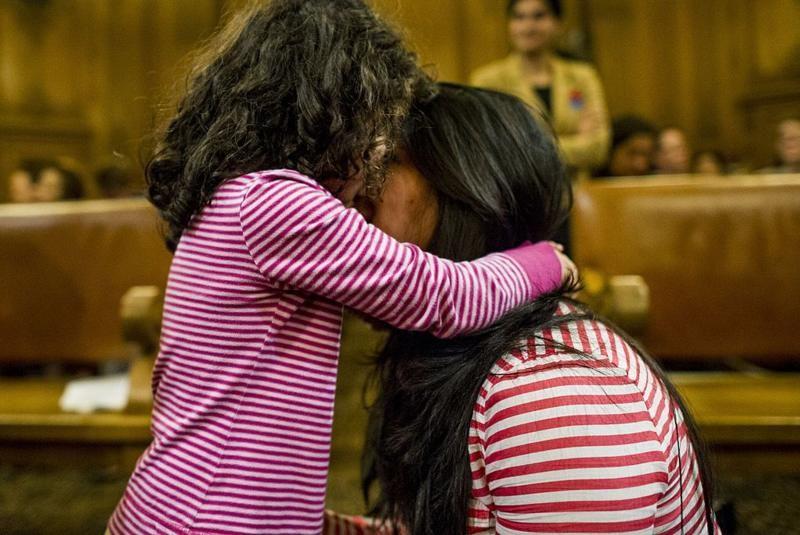 Criança abraça mulher adulta em sala de julgamento