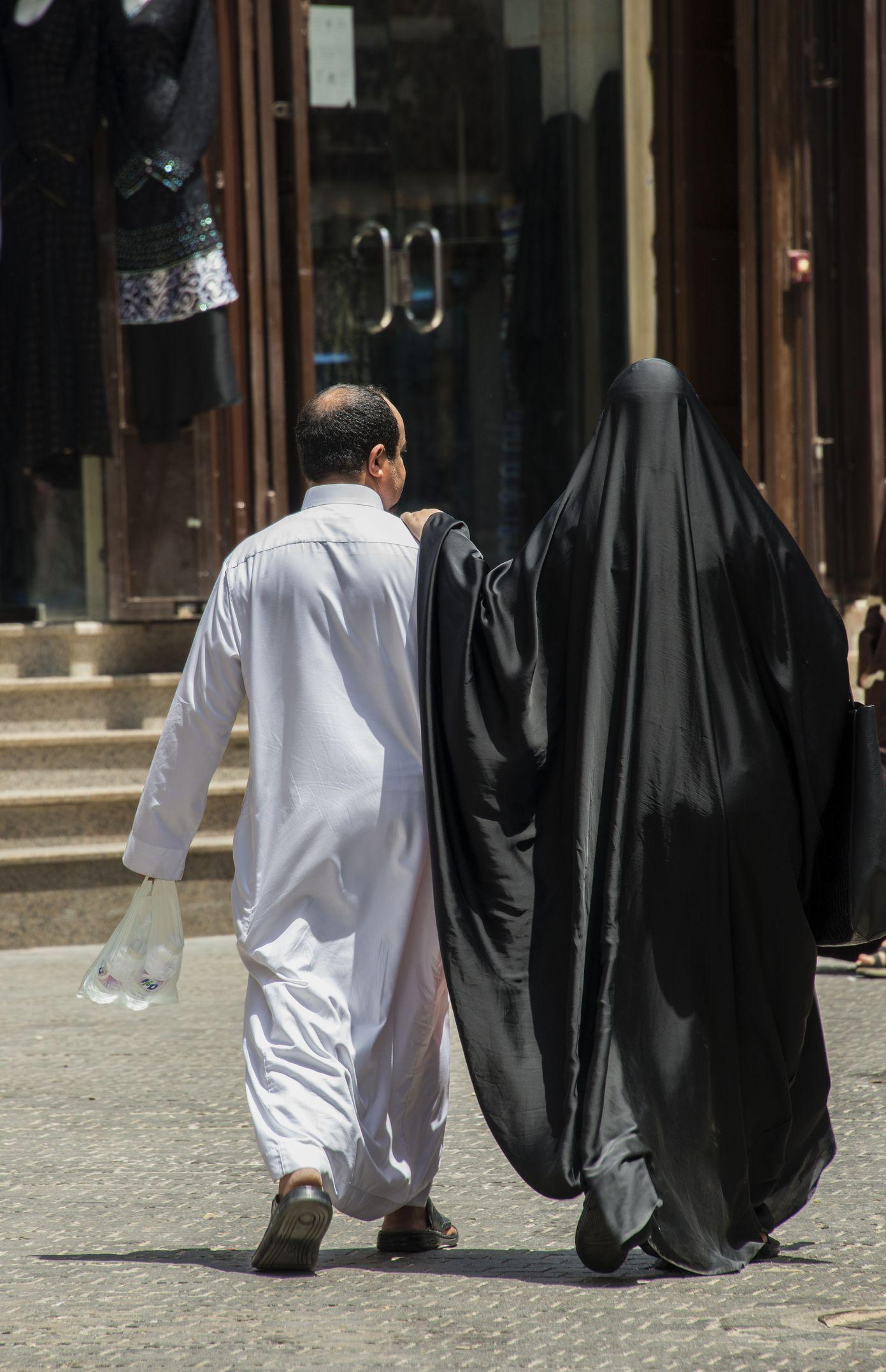 Una pareja saudita camina por las calles de Al Balad, están vestidos con la vestimenta tradicional.