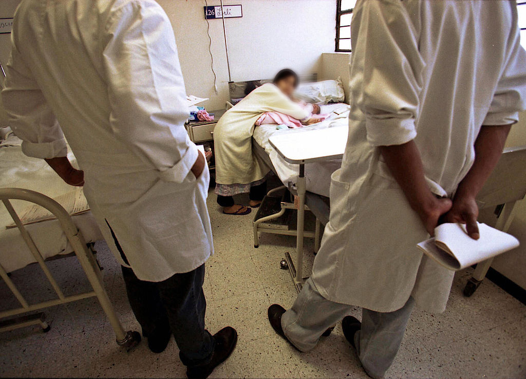 Dos doctores observan a una joven que atiende a su recién nacido en un hospital peruano. a su bebé en un