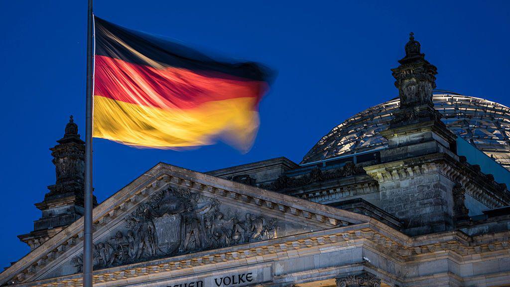 La bandera alemana ondea sobre el edificio del parlamento.