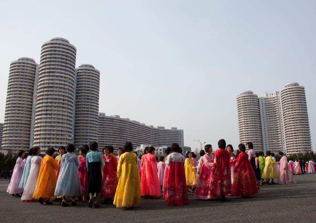 Mujeres vestidas con el traje tradicional frente a unos bloques de apartamentos.