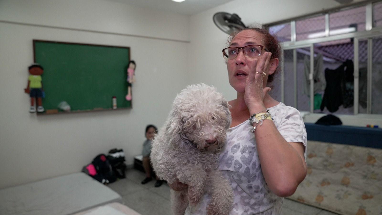 Roselaine da Silva segurando um cachorro em igreja onde está abrigada