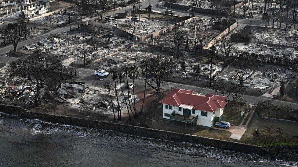 Una casa de techo rojo intacta, rodeada de las cenizas y escombros dejados por los incendios en Maui