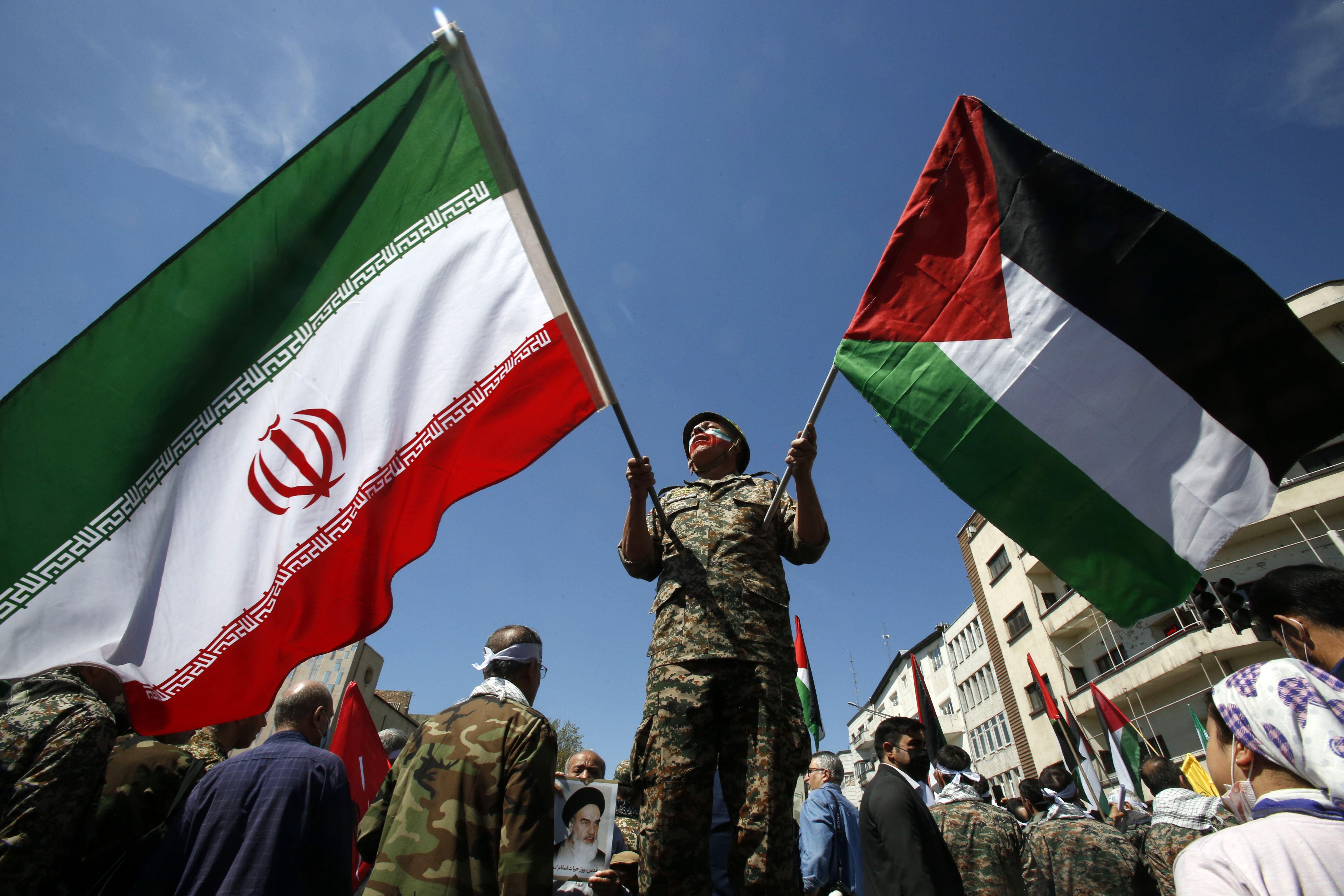 رجل إيراني يلوّح بالعلمين الإيراني والفلسطينين خلال مسيرة بمناسبة يوم القدس في طهران