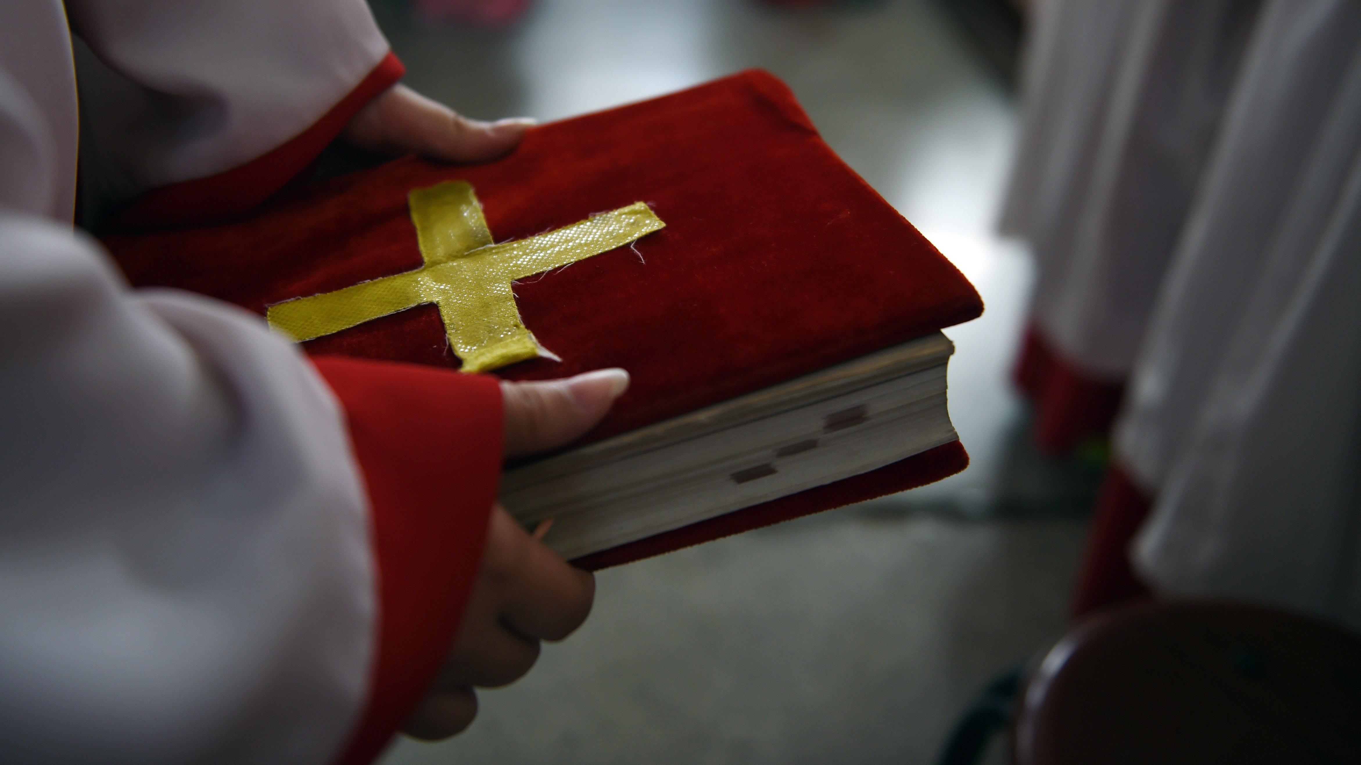 Seorang pelayan altar memegang teks Alkitab saat misa di Gereja Katolik Zhongxin Bridge di Tianjin