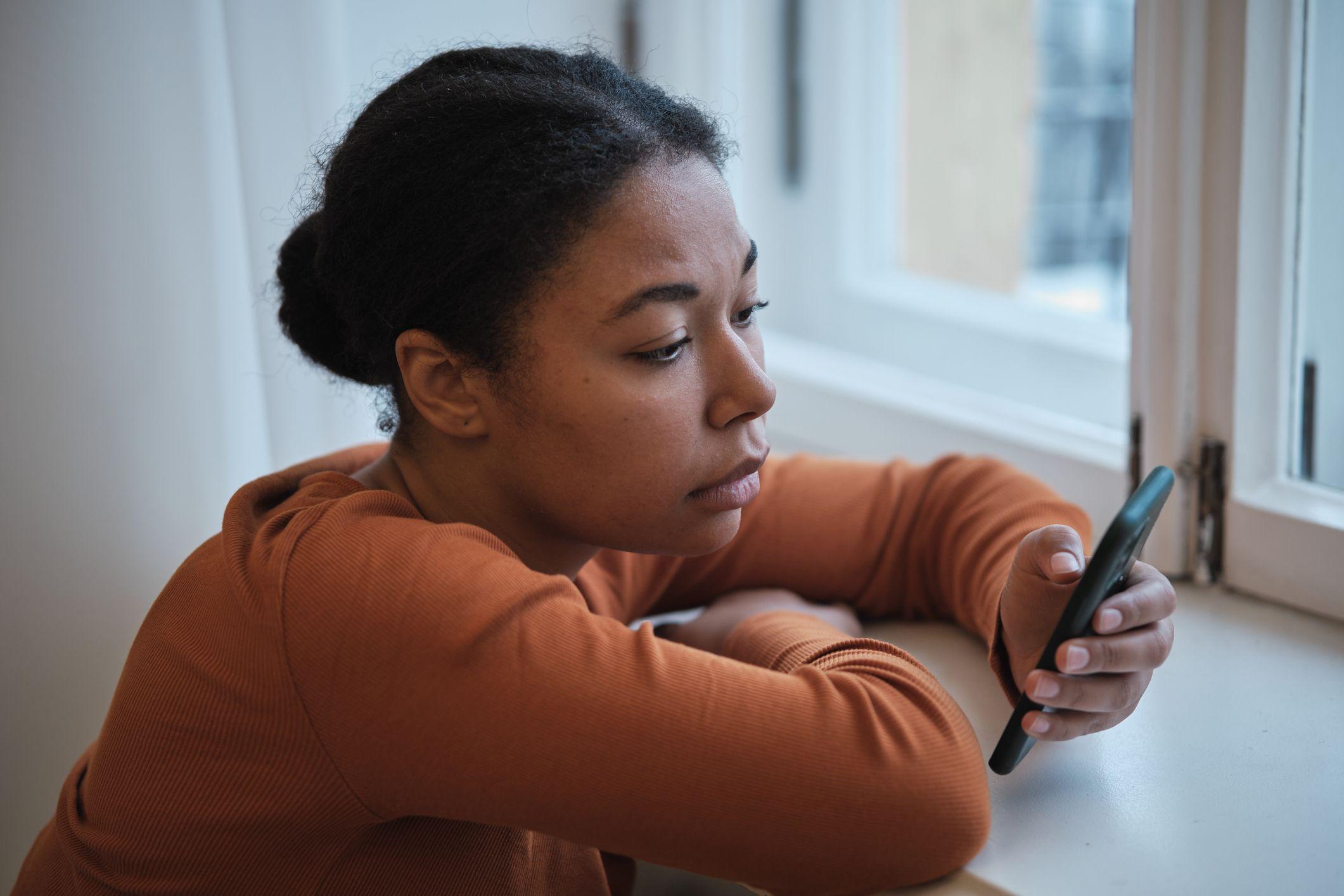 Mulher olhando preocupada para o telefone