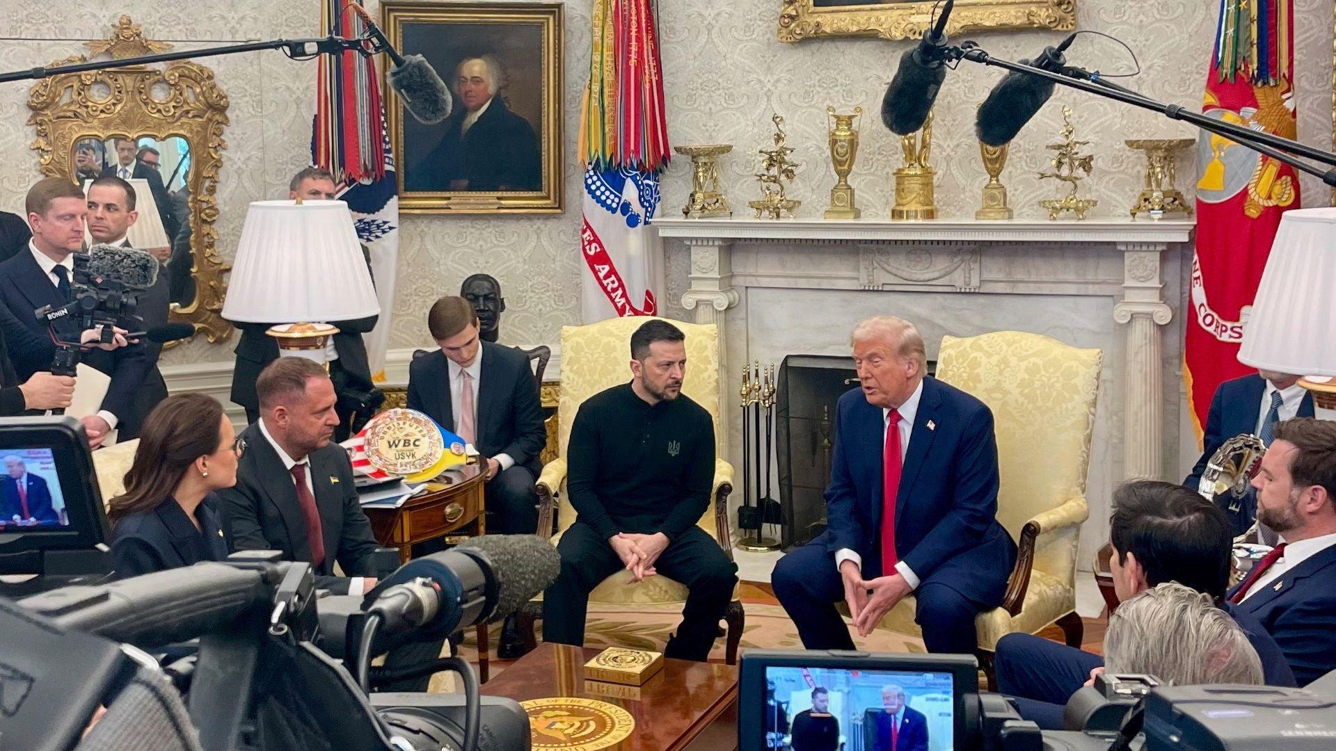 Ukrainian President Volodymyr Zelensky sat in the oval office next to US President Donald Trump while members of the press surround them. 