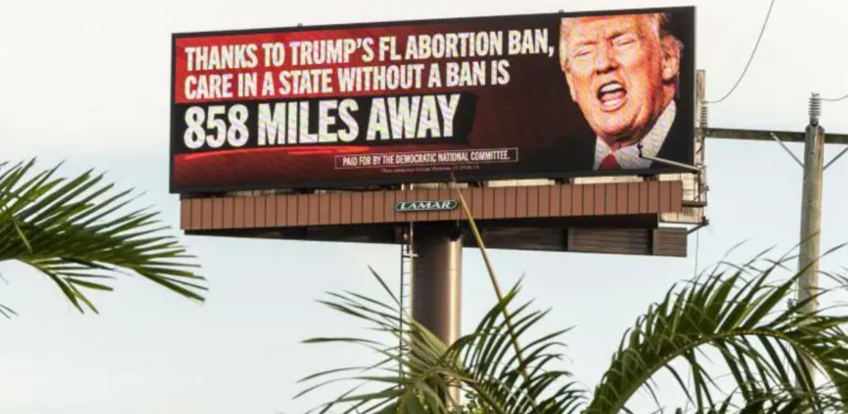 Cartaz com rosto de Donald Trump e dizeres sobre a política de proibição de aborto na Flórida