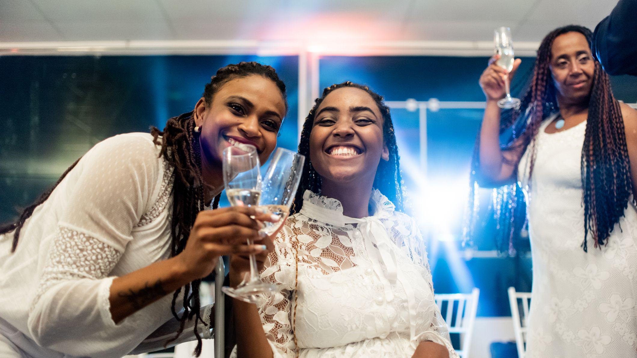 Mulheres vestidas de branco bebendo vinho espumante em taças