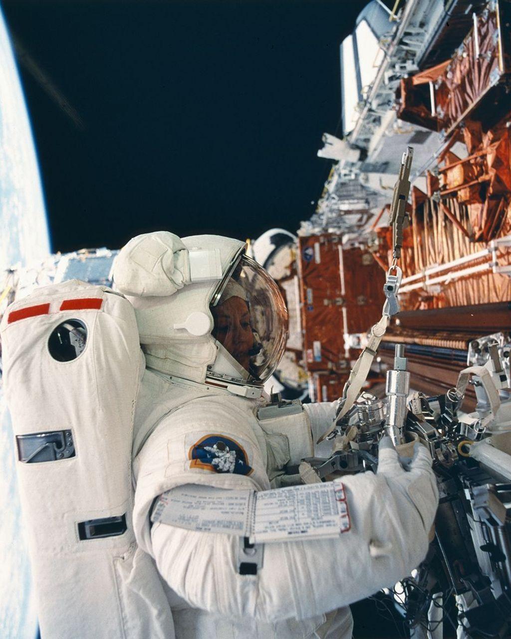 Uma astronauta trabalhando no espaço, segurando uma nave espacial