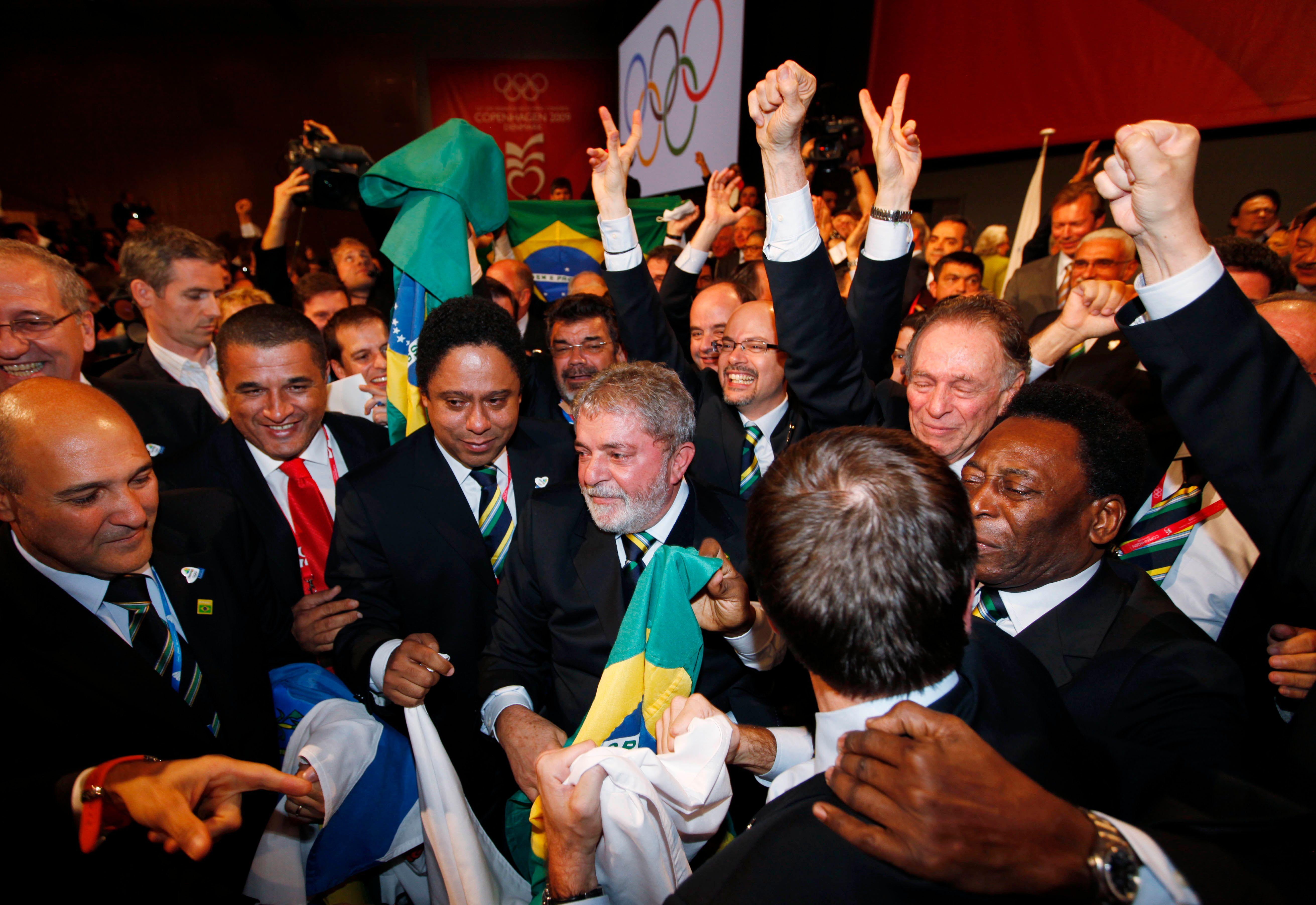 Lula celebra con la bandera de Brasil rodeado de personas en 2009 que Río de Janeiro fuera elegido sede de las Olimpíadas 2016