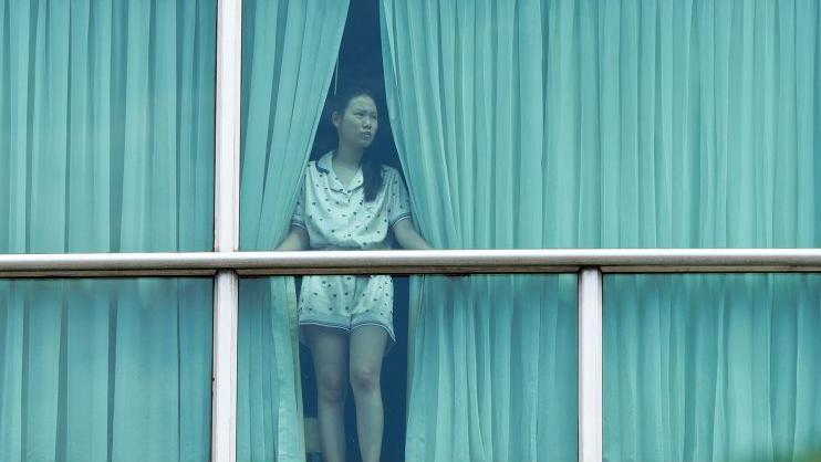 Mujer mira por la ventana de hotel en Panamá.