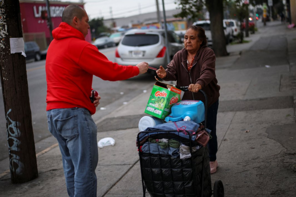 Ron Gochez, voluntario del grupo de defensa de los derechos de los inmigrantes Unión del Barrio, entrega una tarjeta roja de "conozca sus derechos" a una mujer mientras patrulla para la actividad del Servicio de Inmigración y Control de Aduanas de EE. UU. en el sur de Los Ángeles, California, EE. UU., el 5 de marzo de 2025. REUTERS/Daniel Cole