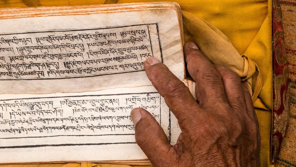 Seorang biksu membalik halaman kitab Tibet.