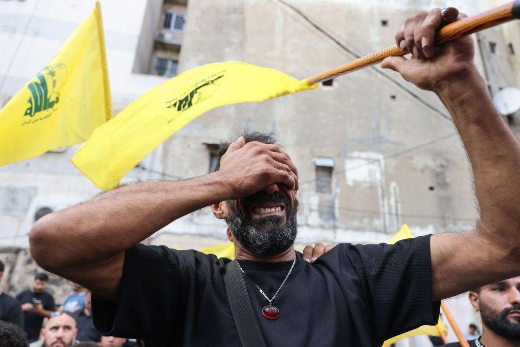 Homem chorando com bandeira do Hezbollah