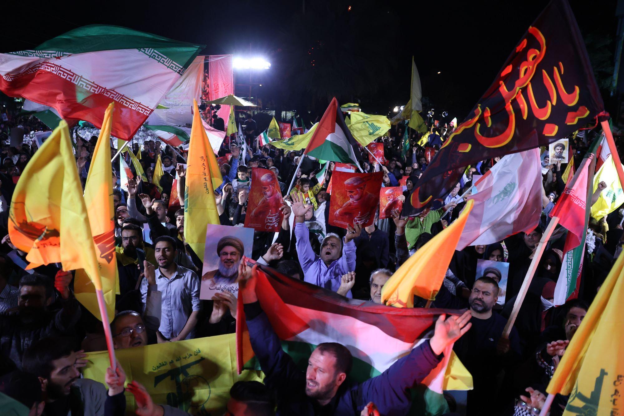 Iranianos comemorando com bandeiras e cartazes na rua à noite