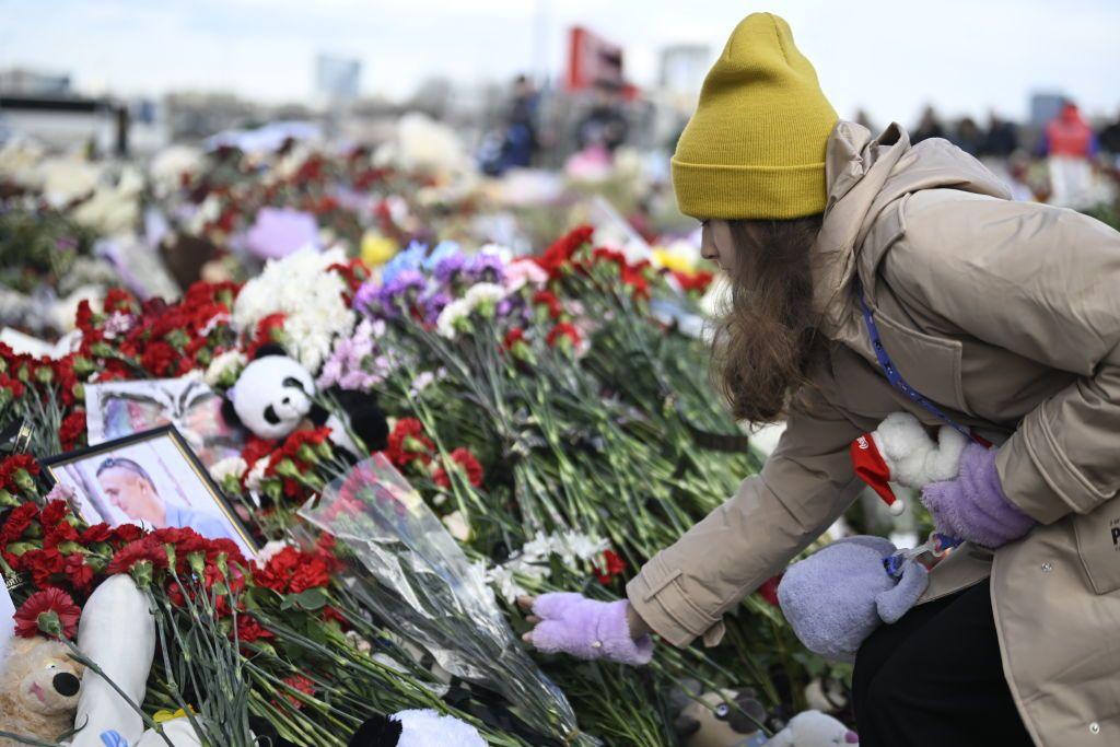 Pessoas deixando flores em memorial improvisado perto da casa de shows Crocus City Hall, em Moscou, após ataque mortal, em março de 2024.