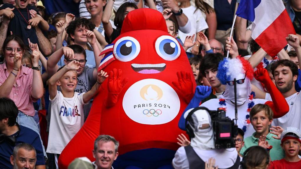 Maskot Olimpiade Paris 2024 berada di tengah penonton selama pertandingan rugby antara Tim Australia dan Tim Samoa di Stade de France, Prancis.