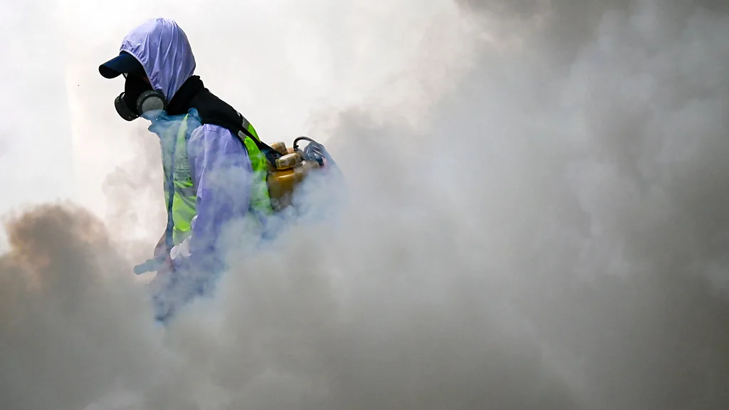 Homem com aparato de segurança aplica fumaça com substância contra vírus zika em áreas afetadas pelo problema