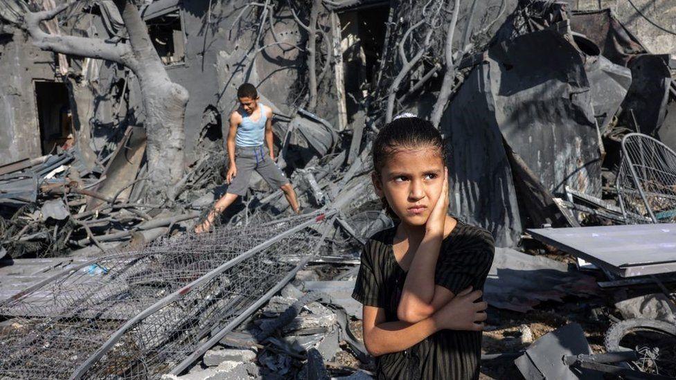 Una niña entre los escombros de un edificio.