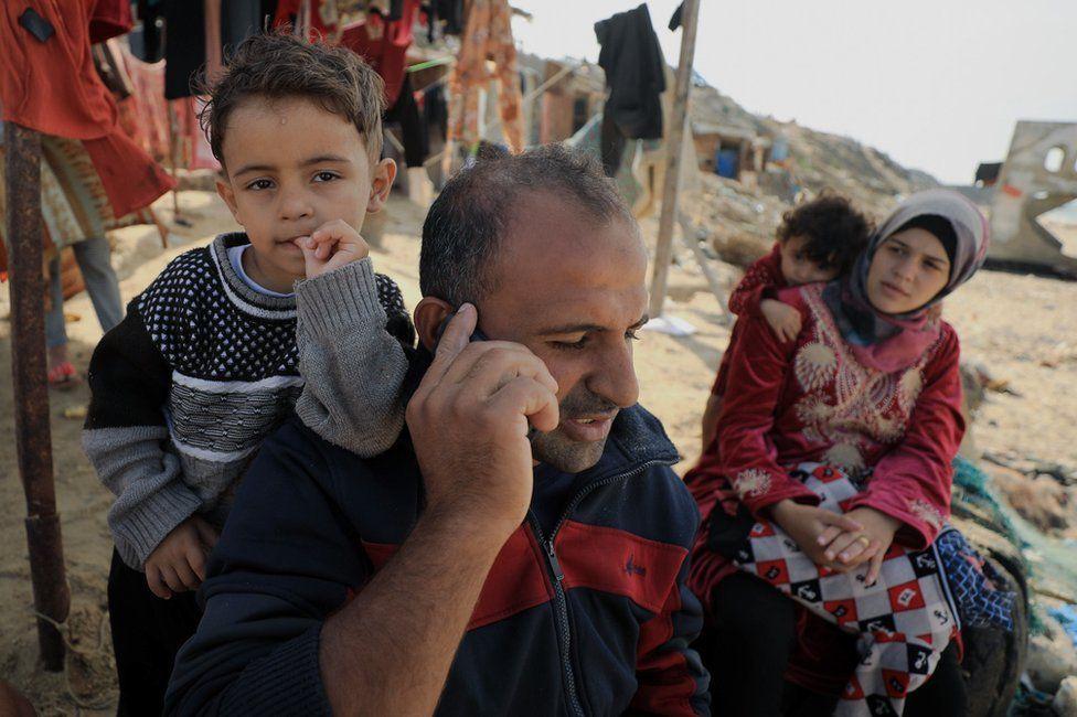 Mahmoud al-Motawag, su esposa Duaa y sus hijos, esperando a que se seque su ropa en la playa de Deir al-Balah.
