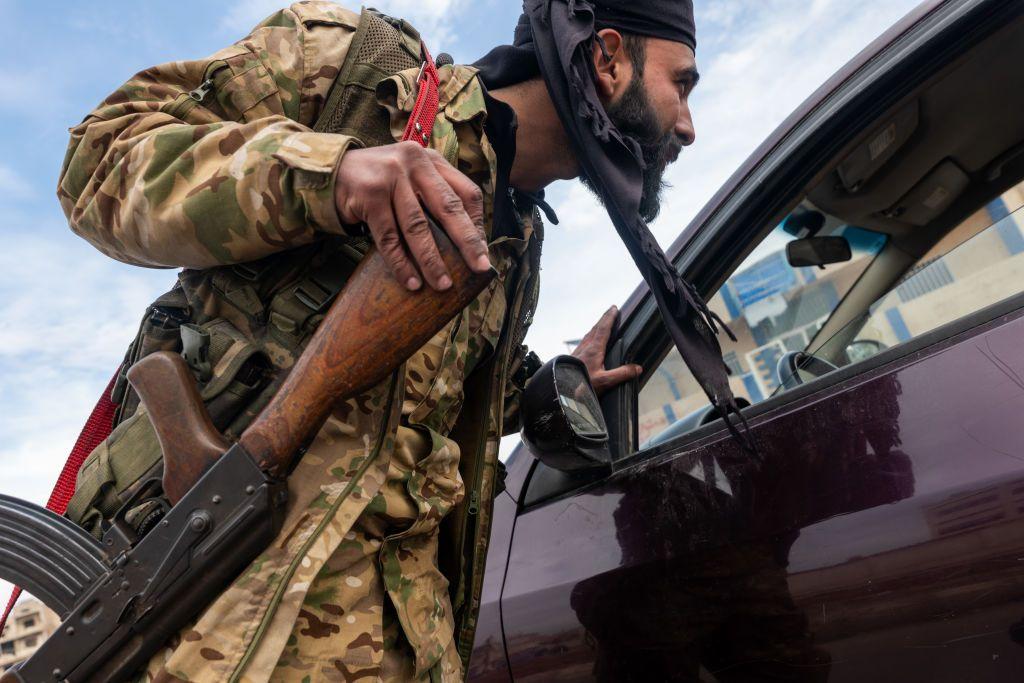 مسلح من هيئة تحرير الشام يتحقق من هوية المارة عند نقطة تفتيش في مدينة حمص في 22 يناير/كانون الثاني 2025 في حمص، سوريا