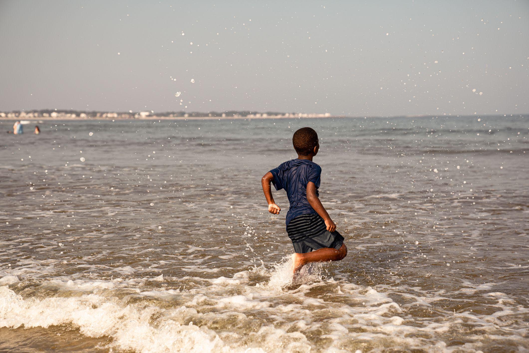 a boy running into a body of water