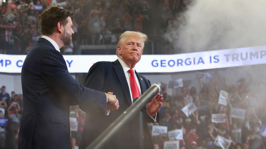 Donald Trump apertando a mão de seu vice J.D. Vance, durante comício na Geórgia em agosto